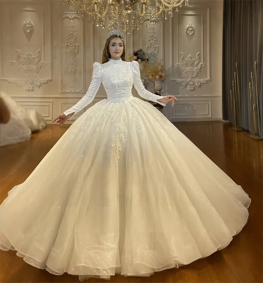 Front perspective of an elegant Muslim wedding dress with intricate floral lace embroidery, a modest high-neck design, and a sweeping, sparkling white skirt.
