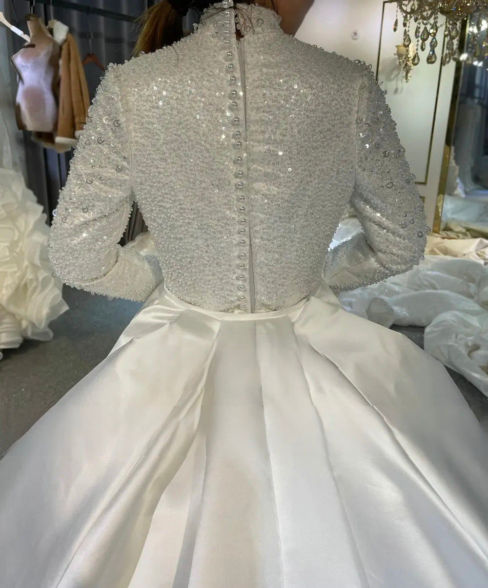 Close-up back view of a modest beaded wedding dress bodice, featuring a high collar and a traditional row of elegant pearl buttons for a refined, detailed bridal look.