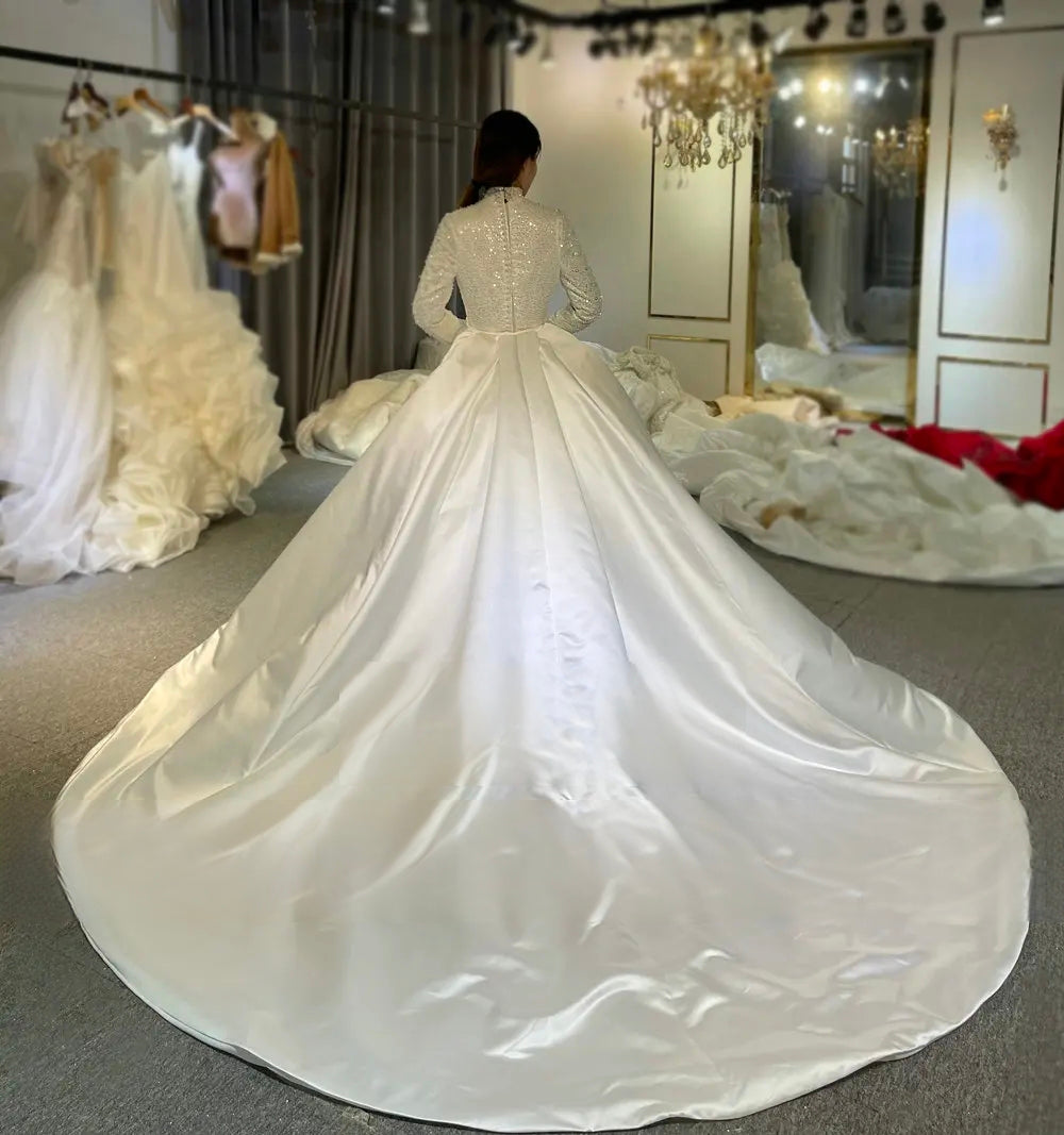 Full back view of a luxury Muslim satin wedding dress with a long, majestic train on a detachable overskirt, highlighting the grand and elegant 2-in-1 silhouette.