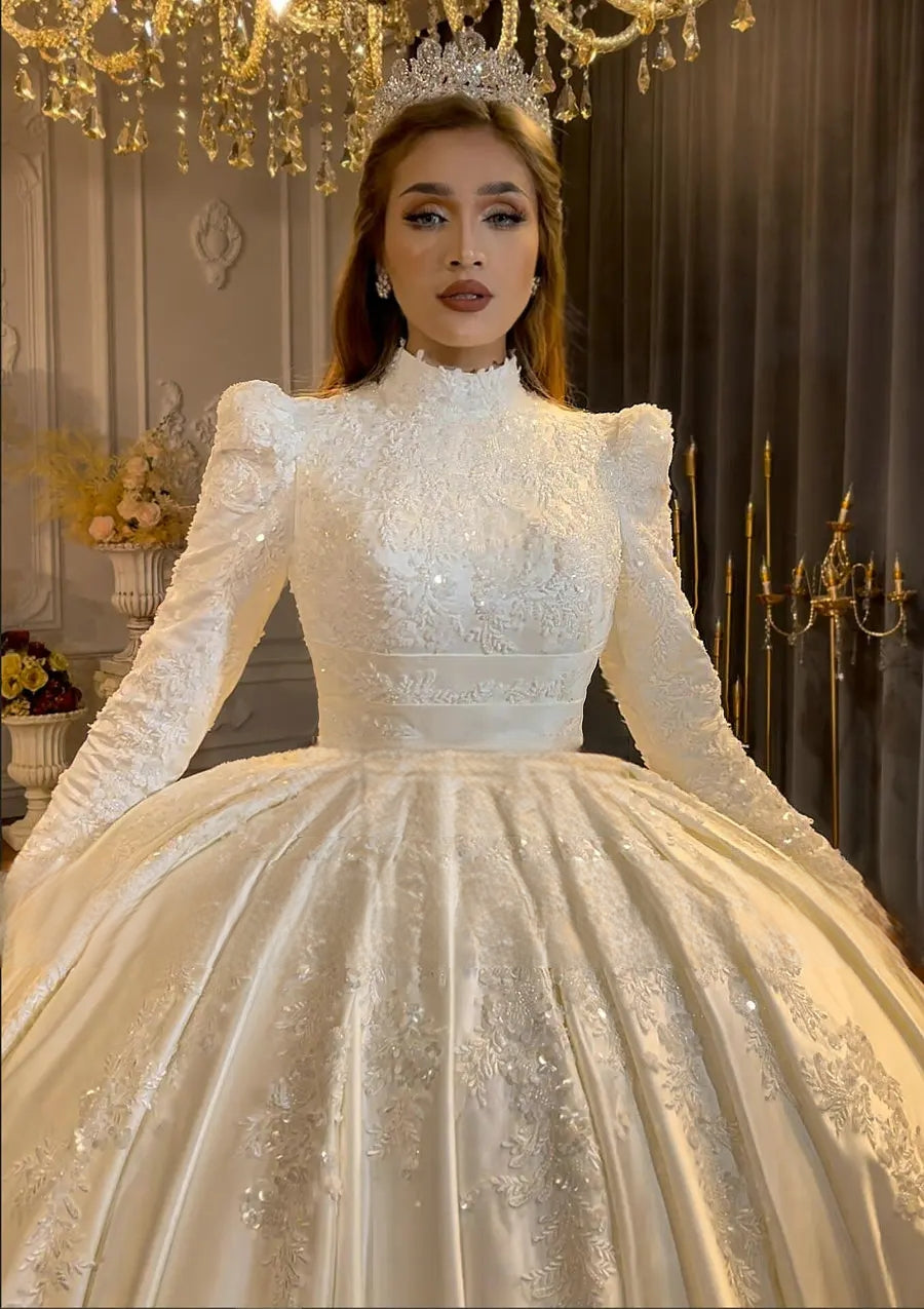 Close-up of a modest wedding dress bodice showcasing intricate heavy beading, a high-neck collar, and elegant long sleeves with puffed shoulder details.