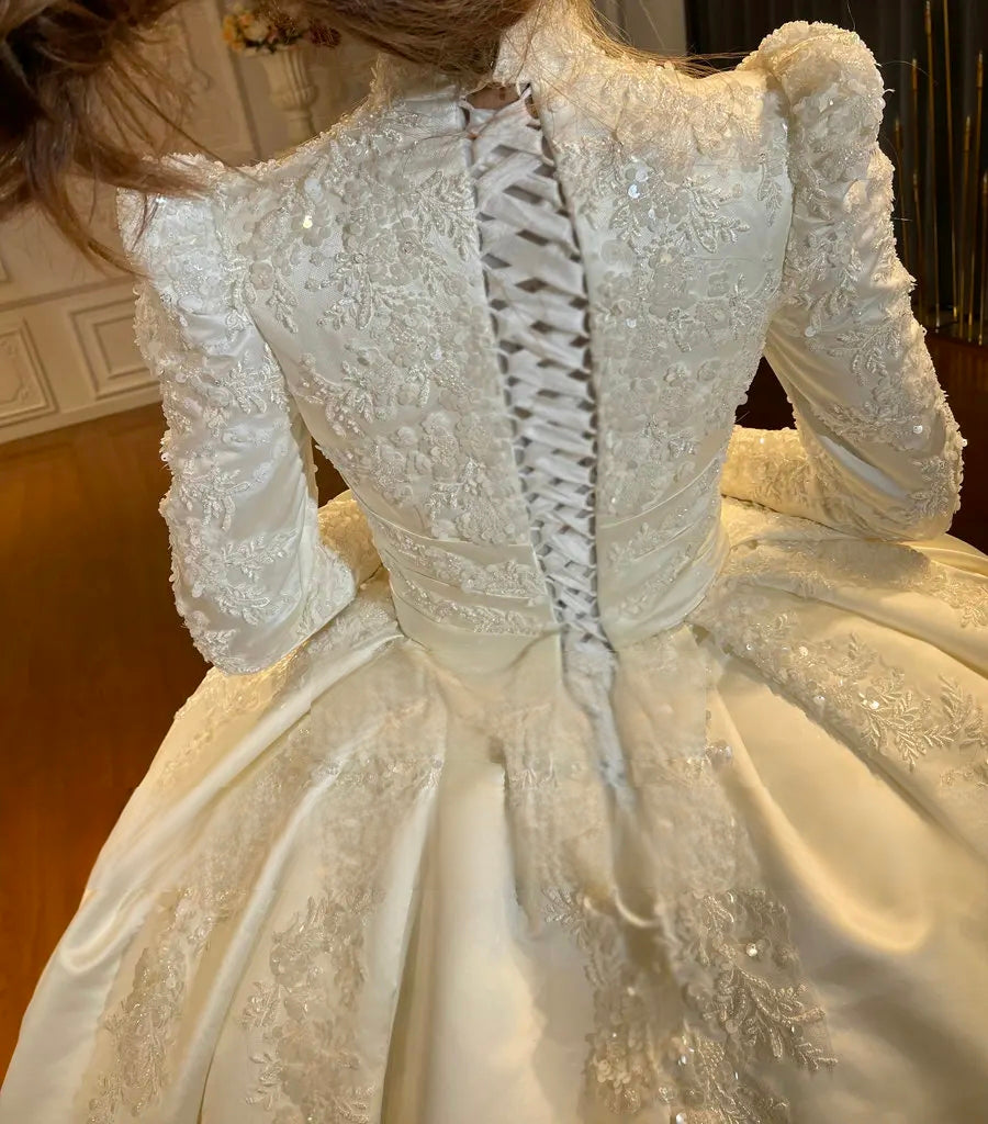 Detailed close-up of the elegant corset lace-up back and shimmering floral lace embroidery on a modest high-neck wedding gown.