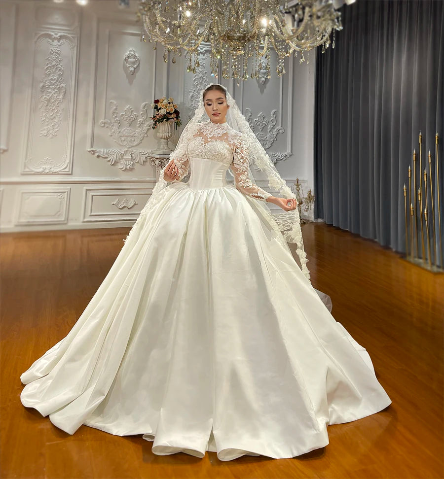 Glamorous nude wedding dress with a voluminous taffeta skirt, illusion lace top, and a matching floral-trimmed bridal veil.