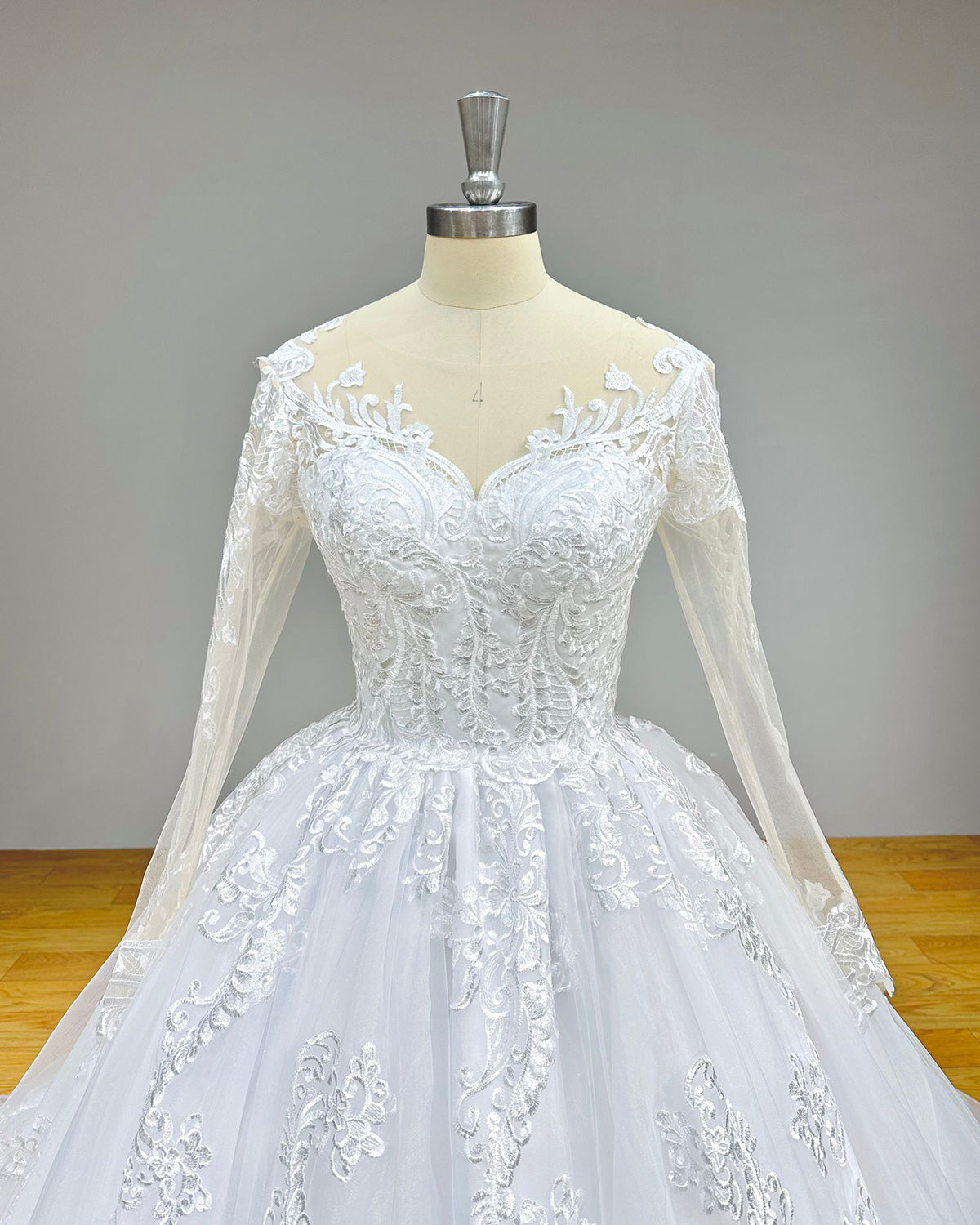 Close-up front bodice detail of a luxury bridal gown on a mannequin, emphasizing the O-neck design and exquisite lace embroidery.