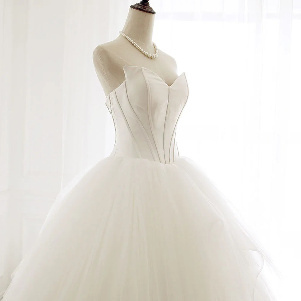 Side view of an elegant off-shoulder A-line wedding dress on a mannequin, showcasing the cascading layers of the tulle skirt and train.