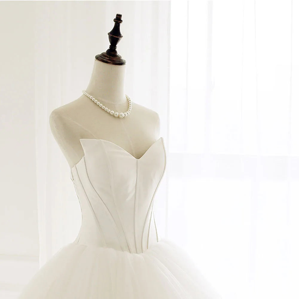 Elegant strapless A-line bridal gown on a mannequin, featuring a refined sweetheart bodice and a pearl necklace accessory.