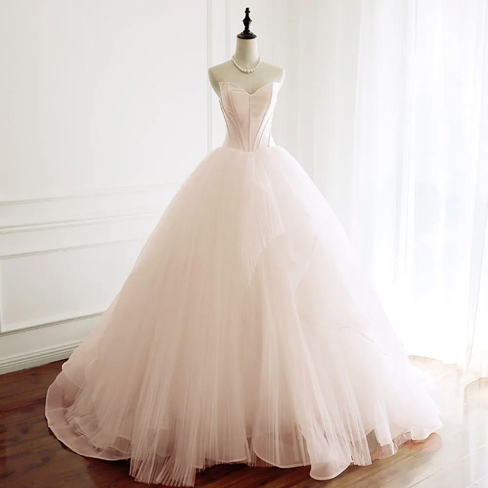 Side-profile view of a strapless A-line bridal dress on a mannequin, highlighting the voluminous tulle skirt and elegant train.