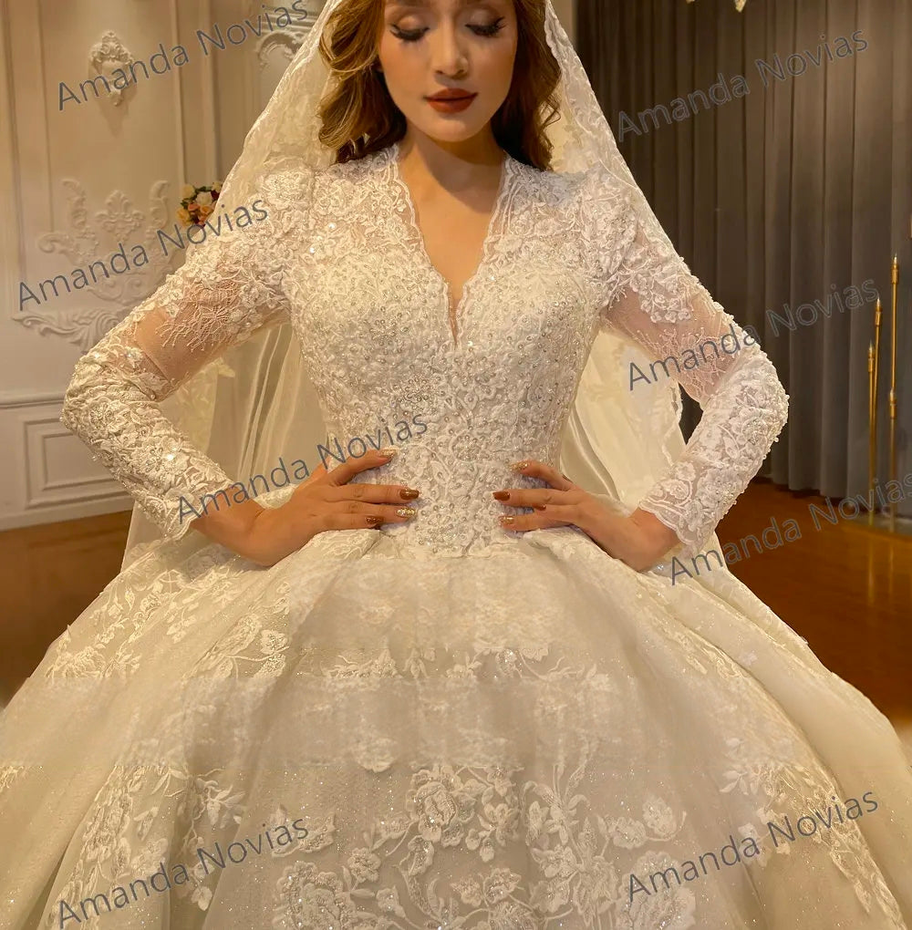 Close-up detail of the plunging V-neckline and intricate hand-beaded lace appliques on the bodice of a luxury off-white long sleeve wedding dress.