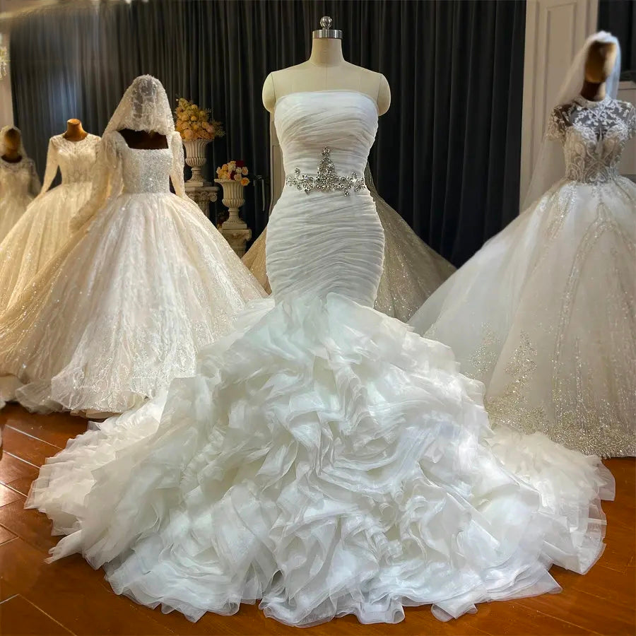 Frontal view of the off-white strapless mermaid wedding dress on a mannequin, showcasing the intricate ruched fabric and sparkling beaded waist embellishment.