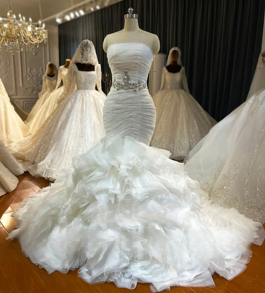Full-length front view of the strapless off-white bridal dress on a mannequin, emphasizing the structured mermaid silhouette and dramatic layered ruffles.