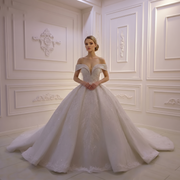 Full-length view of an elegant off-shoulder lace wedding gown with delicate beaded straps and a voluminous A-line skirt.