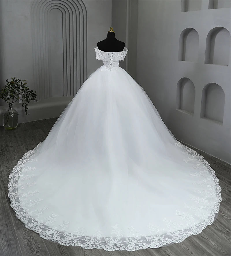 Mid-angle rear shot highlighting the sweeping drape and detailed lace border trailing along the edges of the elegant plus size wedding gown train.