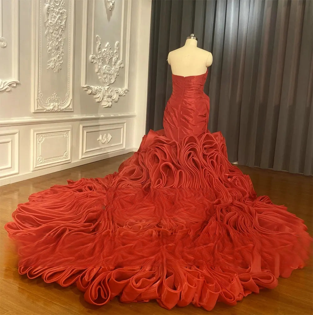 Back view of the romantic red satin bridal gown on a mannequin, emphasizing the corset back and the extensive, voluminous ruffled train.