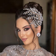 Side profile portrait of a bride showcasing an elegant rhinestone bridal headpiece with a sprawling silver leaf branch design pinned into a high bun updo.