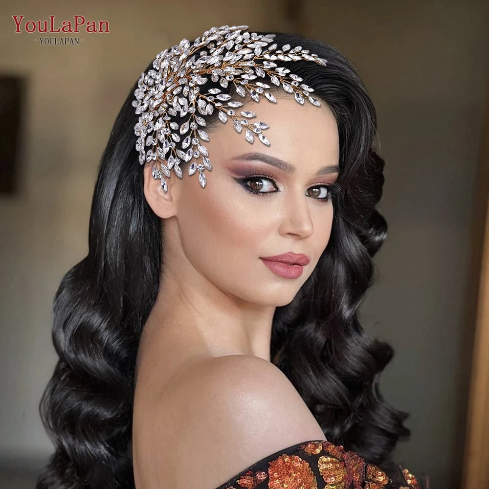 Side view portrait of a bride with long wavy dark hair wearing an elegant rhinestone bridal headpiece featuring a widespread crystal leaf design.