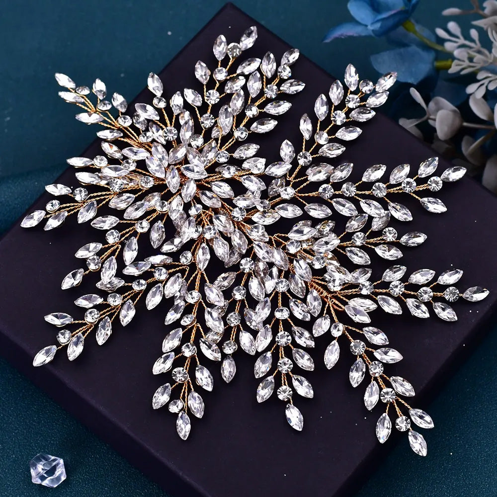 Close-up top view of a luxury silver wedding hair accessory showcasing an intricate branch pattern of clear marquise crystals on a dark gift box.