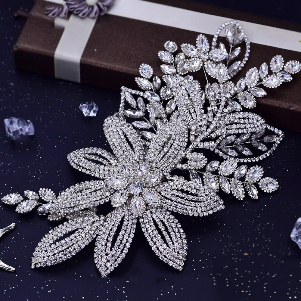 Detailed view of the crystal flower wedding hair comb, highlighting the multi-row rhinestone petals and leaf accents against a brown display box.