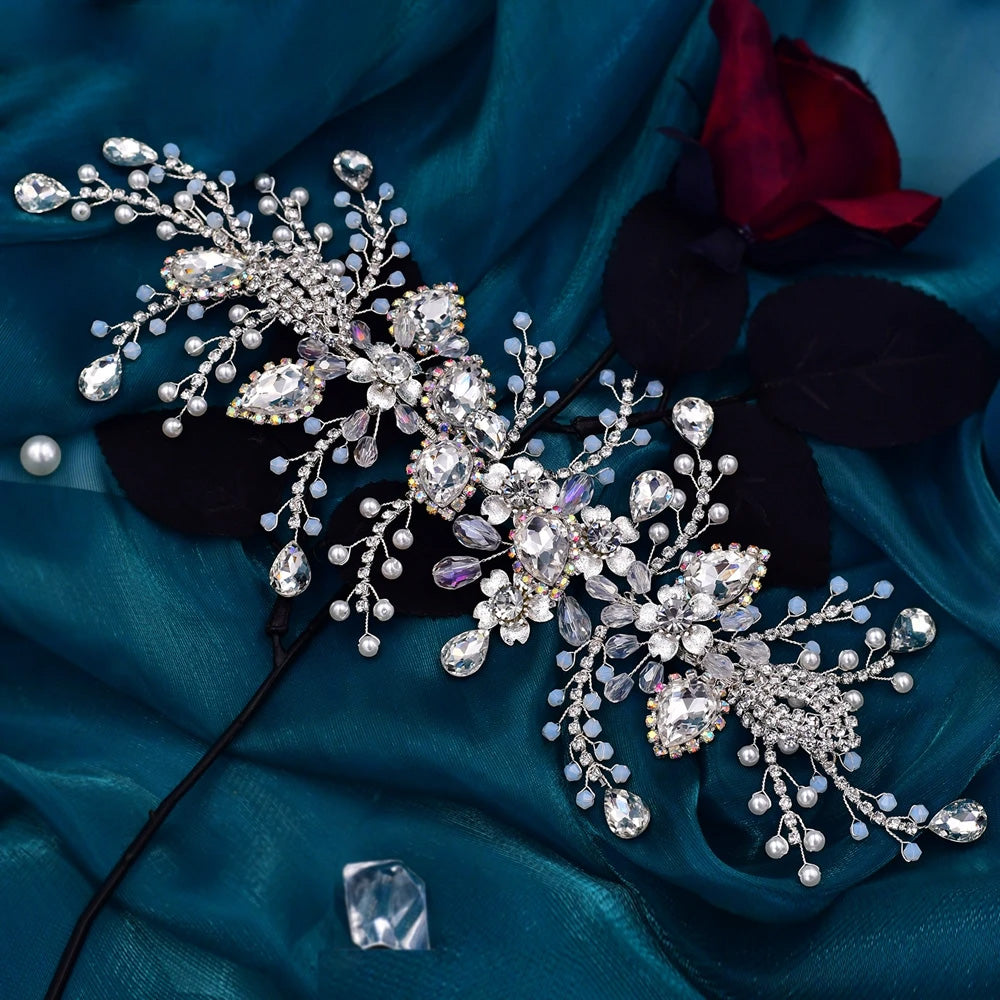 Top-down view of a flexible silver crystal bridal hair vine piece styled over dark fabric with shimmering rhinestones and botanical accents.