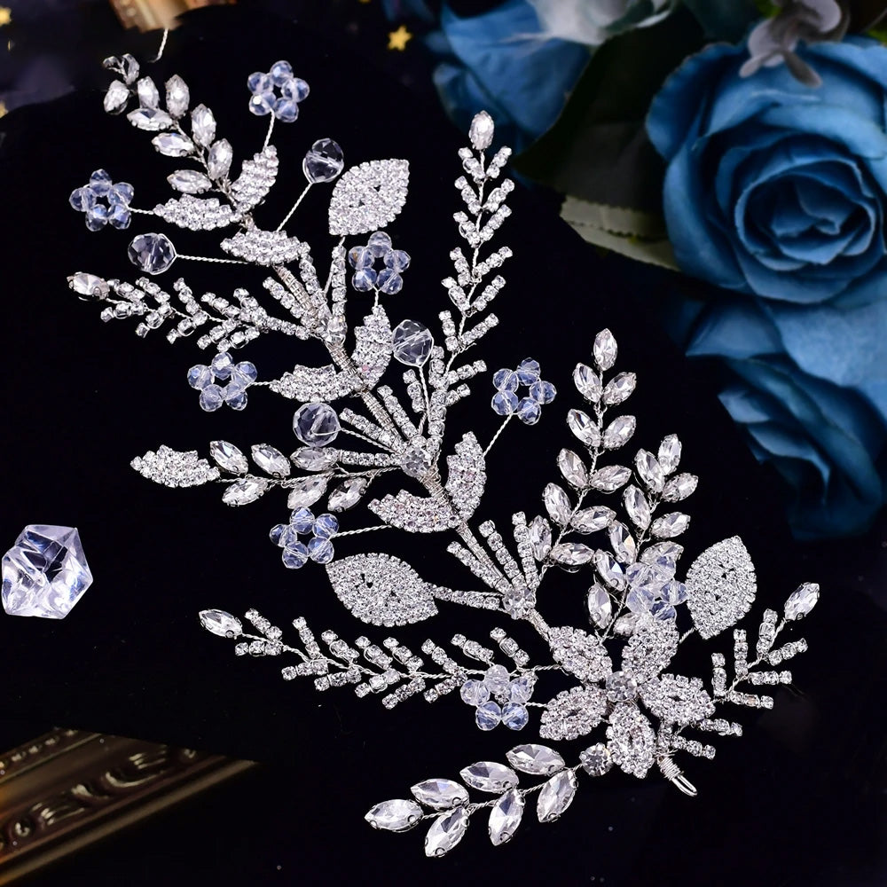High-angle shot of a handcrafted silver bridal comb headpiece featuring clear marquise rhinestones arranged like detailed spray leaves on black velvet.