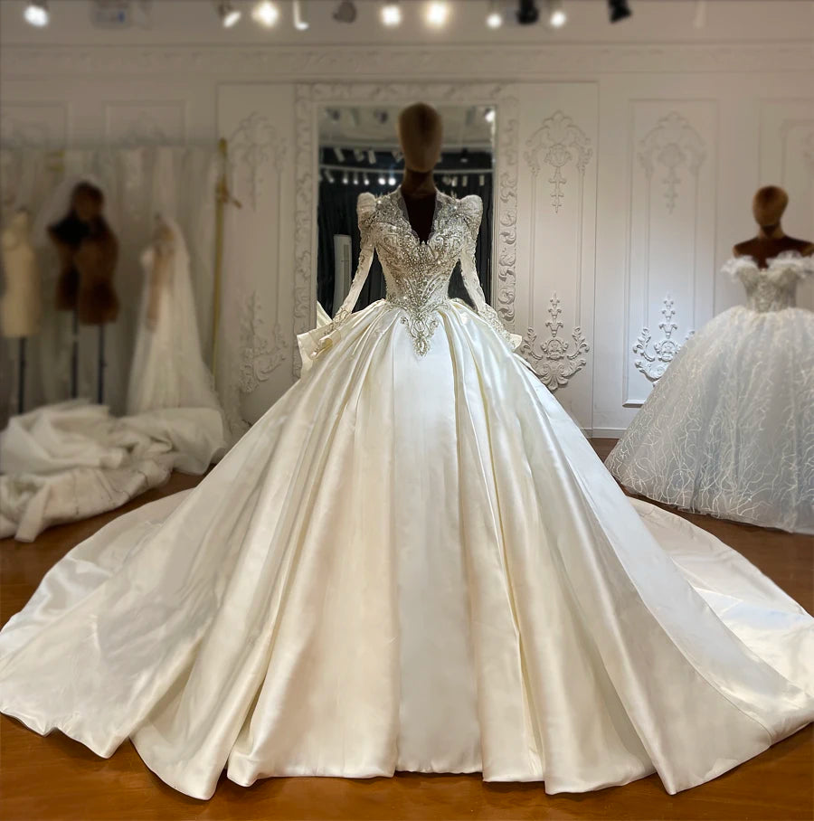 Full front view of an ivory satin A-line bridal dress featuring a deep V-neckline and a heavily beaded silver bodice.