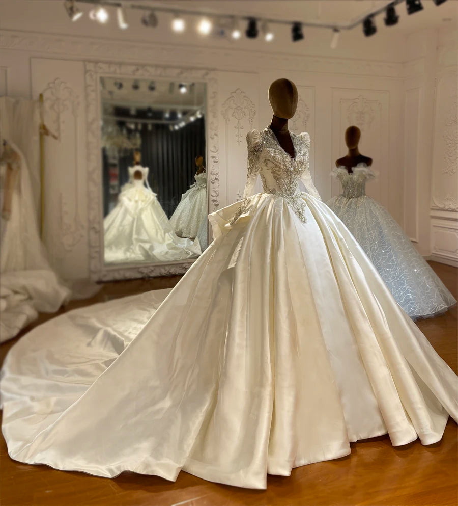 Three-quarter view of a luxury satin wedding gown showcasing structured beaded shoulders and a voluminous A-line skirt.