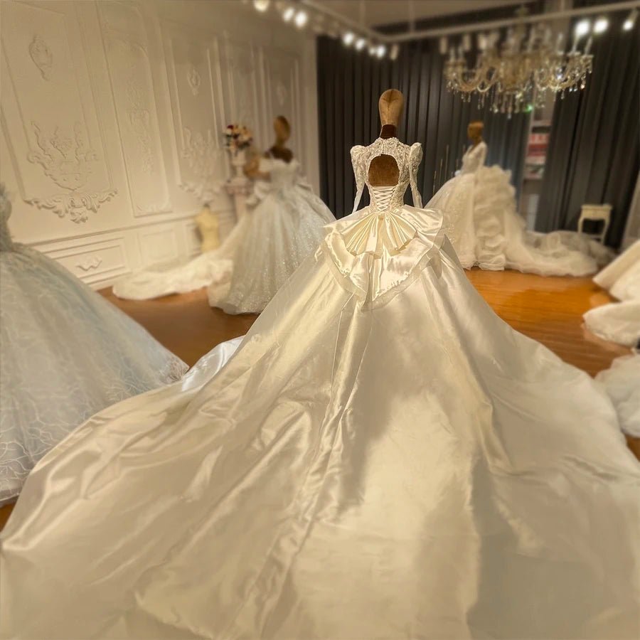Rear view of a satin bridal dress highlighting a keyhole back, lace-up corset detail, and a dramatic cathedral-length train.