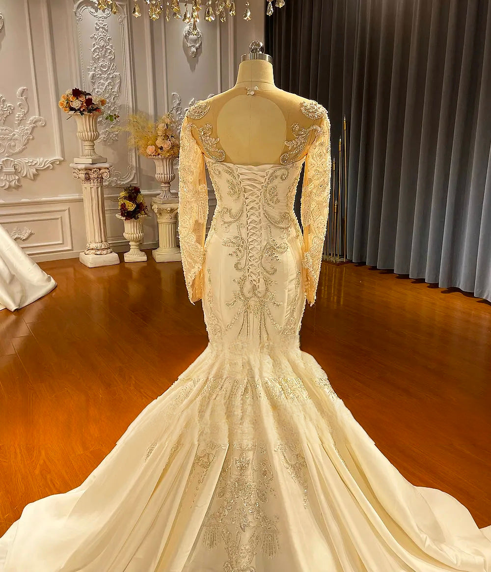 Rear view of the satin mermaid wedding dress on a mannequin, displaying an elegant corset lace-up back and a grand, flowing chapel-length train.