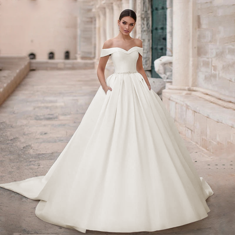 Full-length view of a luxurious satin wedding dress with a voluminous ball gown skirt and a refined off-the-shoulder bodice.