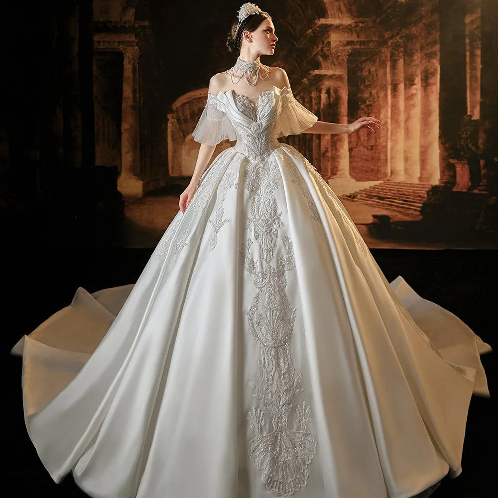 Front full-length display of an elegant satin ball gown wedding dress on a mannequin, featuring a classic boat neckline, structured short sleeves, and a grand box-pleated skirt.