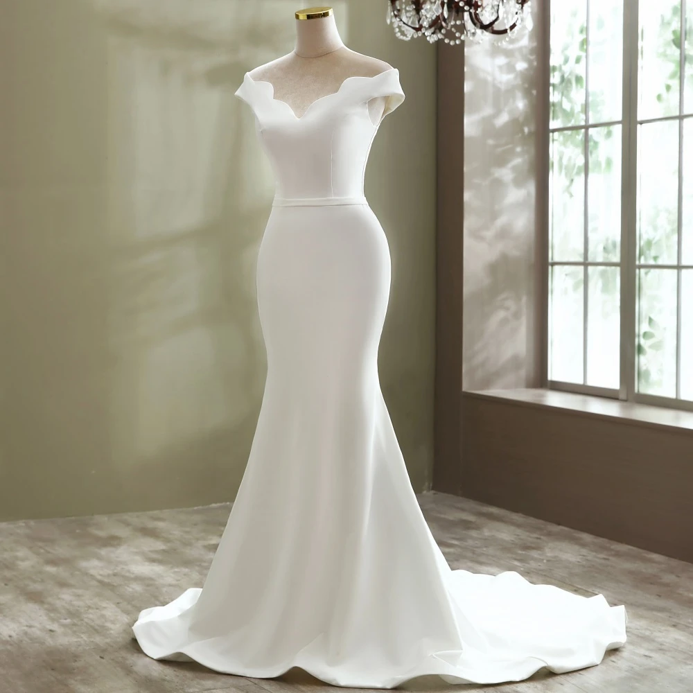A mannequin view of an elegant mermaid wedding dress featuring a scalloped boat neck design and a minimalist, form-fitting silhouette.