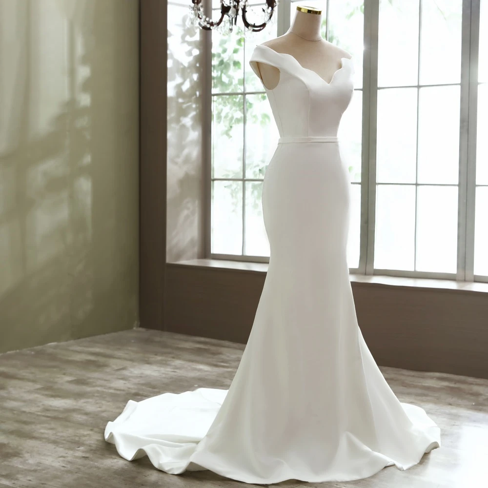 A detailed close-up of the elegant scalloped boat neck neckline on a simple, modern mermaid wedding dress.
