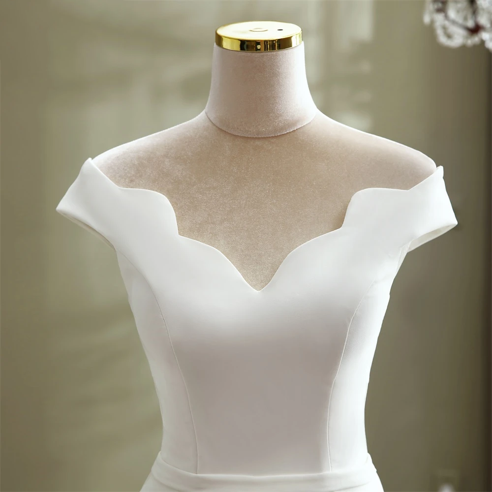 A close-up front view of the minimalist boat neck detail on an elegant mermaid wedding gown.