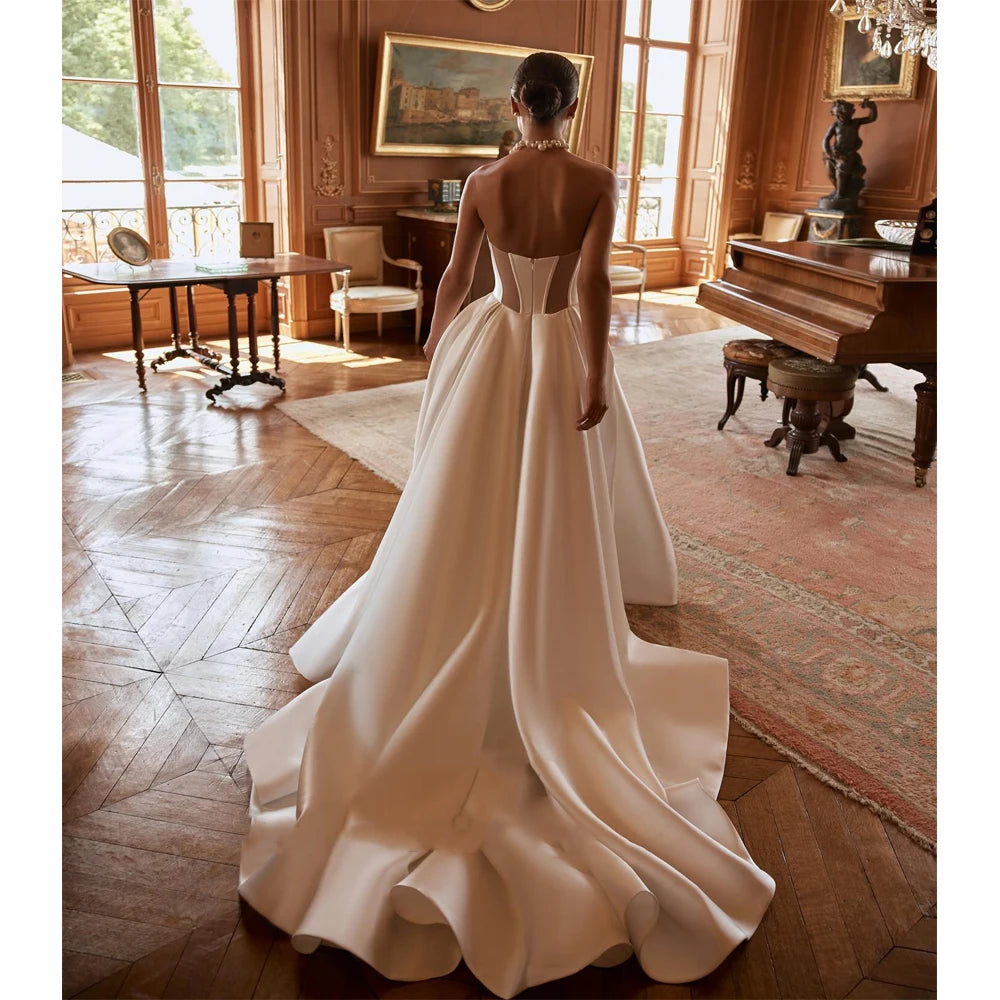 A back view of a bride in a strapless satin wedding gown with a dramatic, fluffy skirt and long sweeping train, photographed in a luxurious vintage-style room.