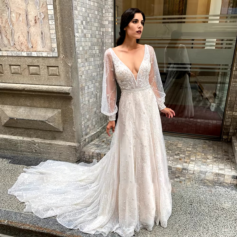 Rear view of the shiny long sleeve bridal gown, showcasing an intricate illusion mesh back decorated with crystal embroidery and a sweeping cathedral-length train.