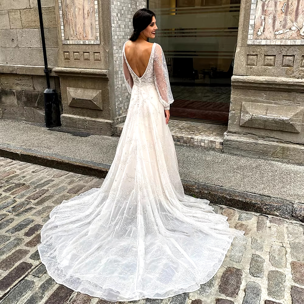 Close-up front shot highlighting the glamorous plunge V-neck bodice, exquisite crystal beadwork patterns, and luxury sequin appliques on the long sheer sleeves.