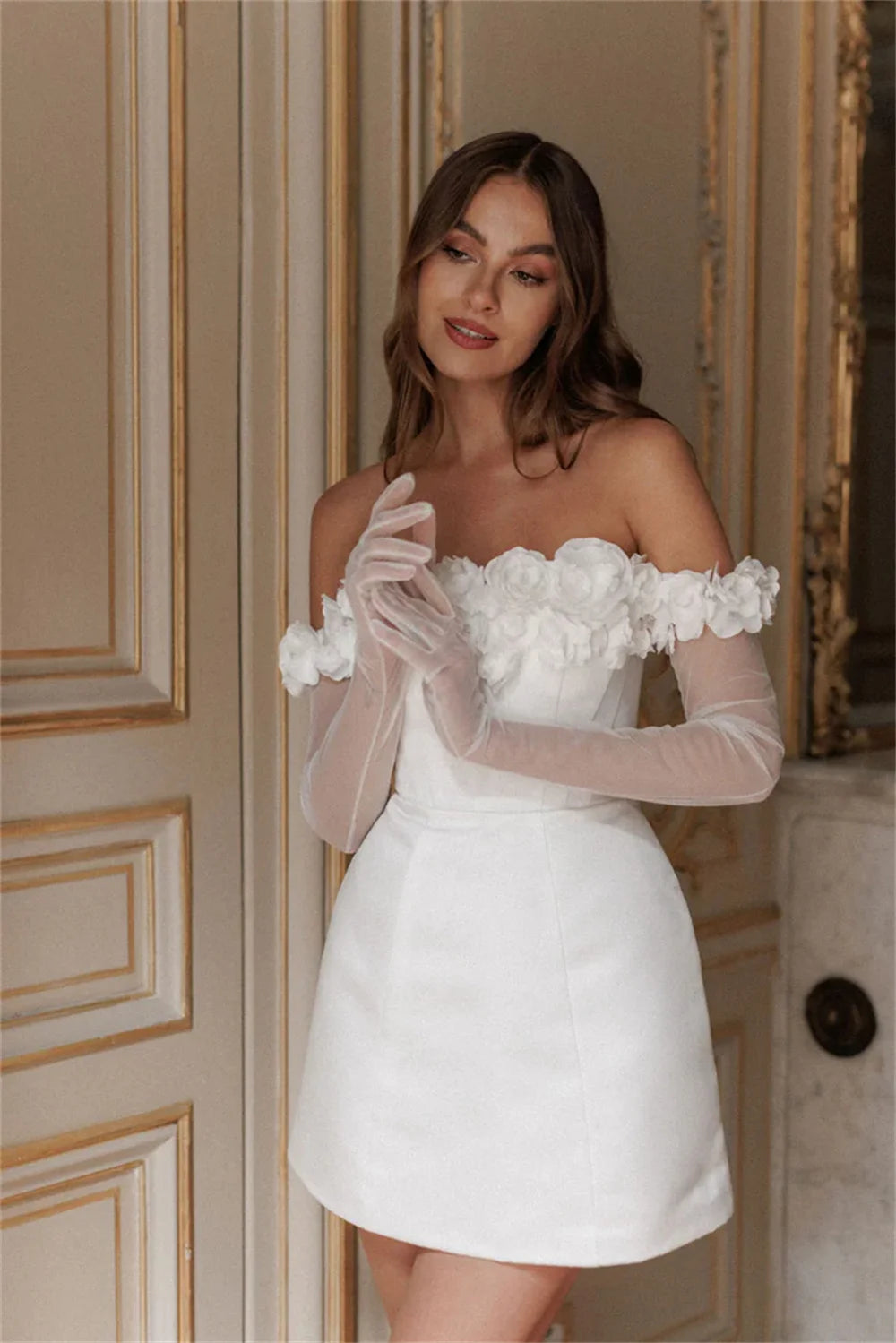 Back view of a white mini bridal dress with off-the-shoulder floral sleeves, showing a structured fit and side leg slit.