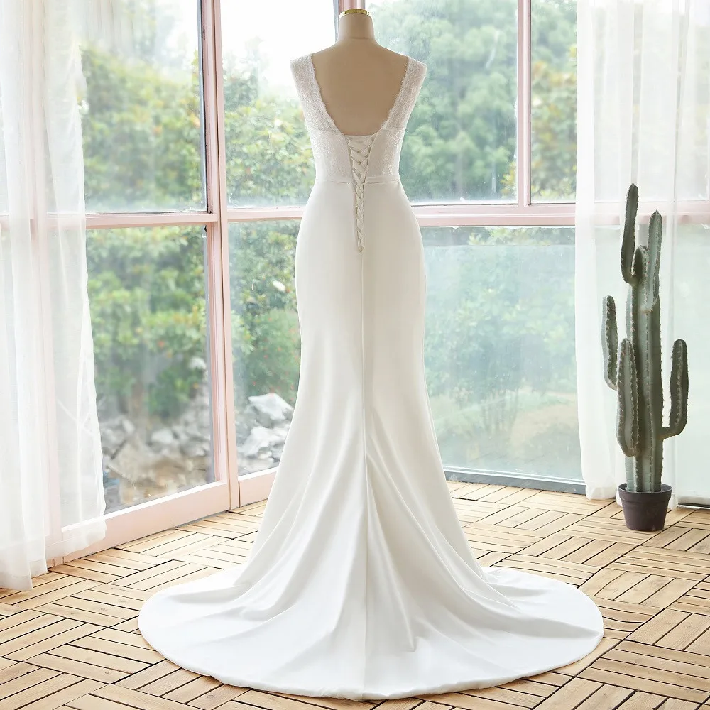 Rear view of an elegant, simple lace sleeveless mermaid wedding dress featuring a lace-up corset back and a flowing train.