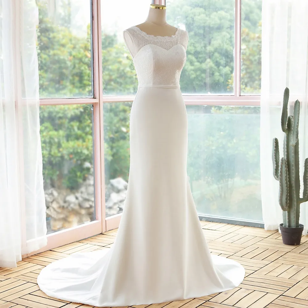 Studio presentation of an elegant, simple lace sleeveless mermaid bridal gown on a mannequin, highlighting the fitted waistline.