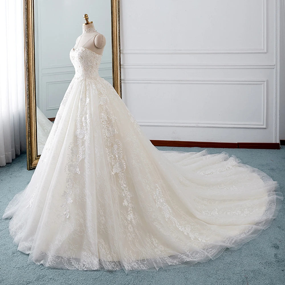 Detailed close-up of a wedding gown bodice featuring floral lace embroidery, pearl beadwork, and detachable ruffled sleeves.