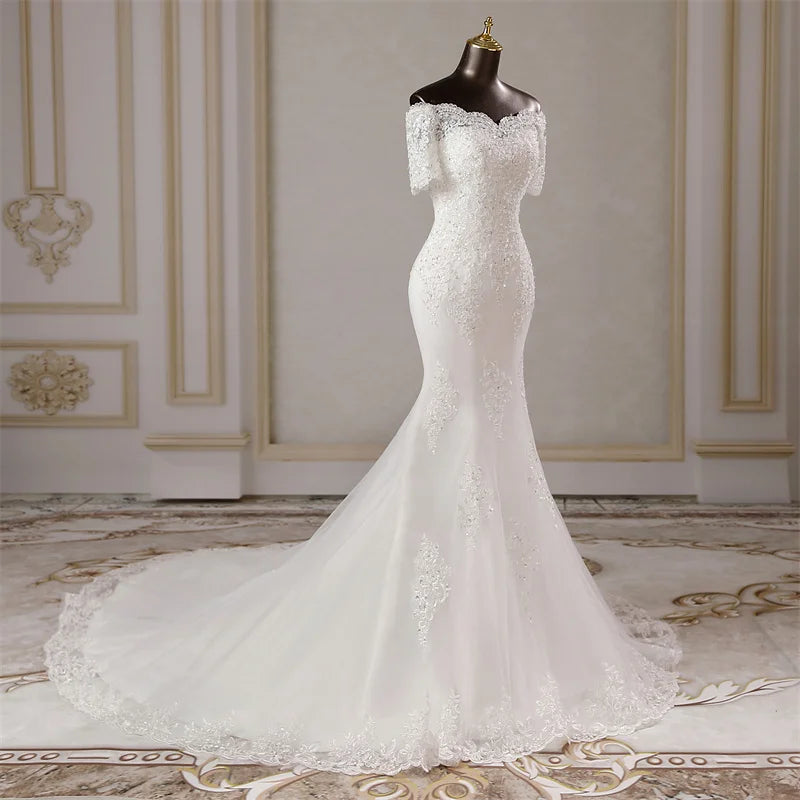 Front view of an elegant, short-sleeve mermaid bridal gown on a mannequin, emphasizing the seamless transition from the lace bodice to the flared skirt.