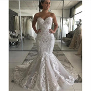 Front view of a model wearing an elegant strapless sweetheart neckline lace mermaid wedding dress with a fitted silhouette and a dramatic flared skirt.