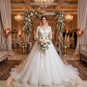 Bride posing in a romantic wedding venue wearing an elegant long-sleeve A-line tulle wedding dress with a satin waist belt.