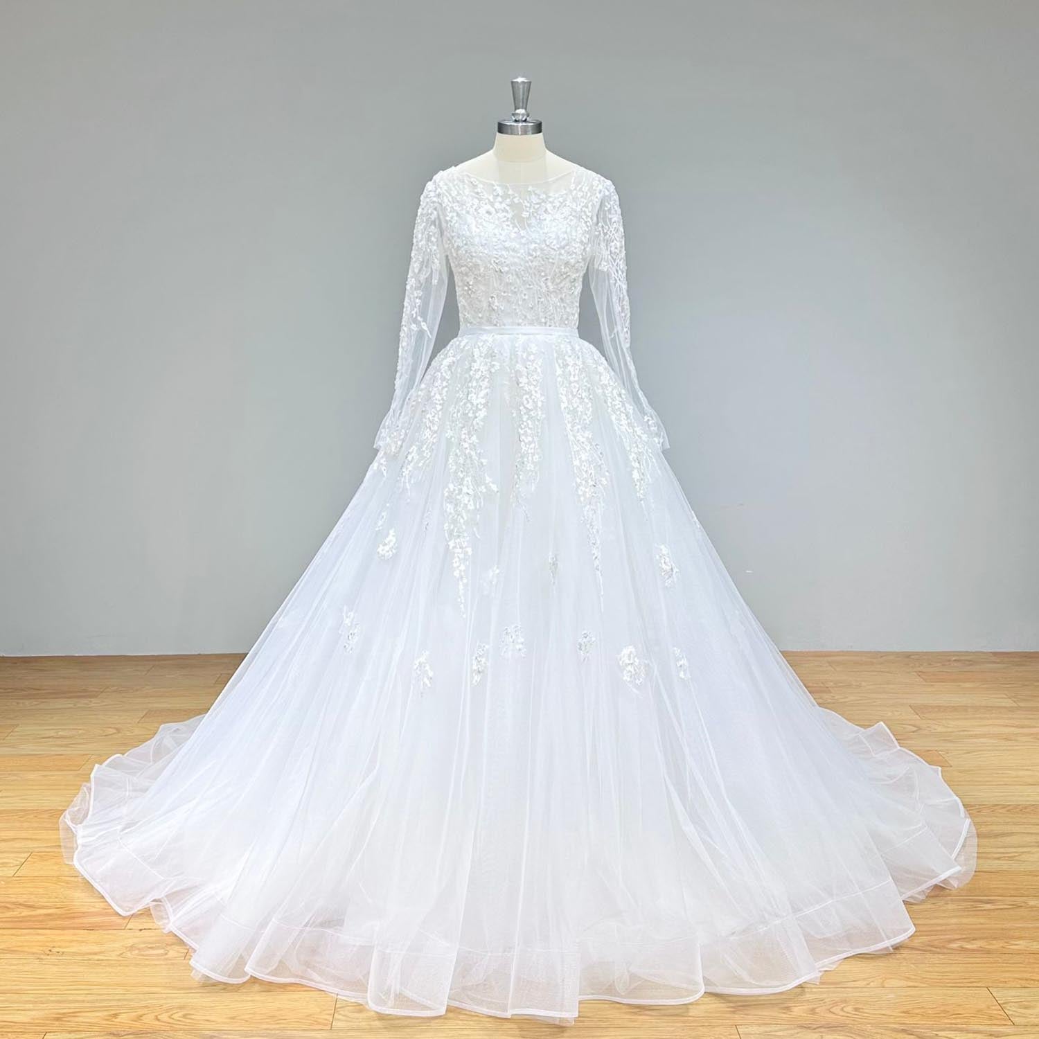 Front full-length view of a long-sleeve A-line tulle wedding dress with an intricate lace bodice and satin belt on a mannequin.