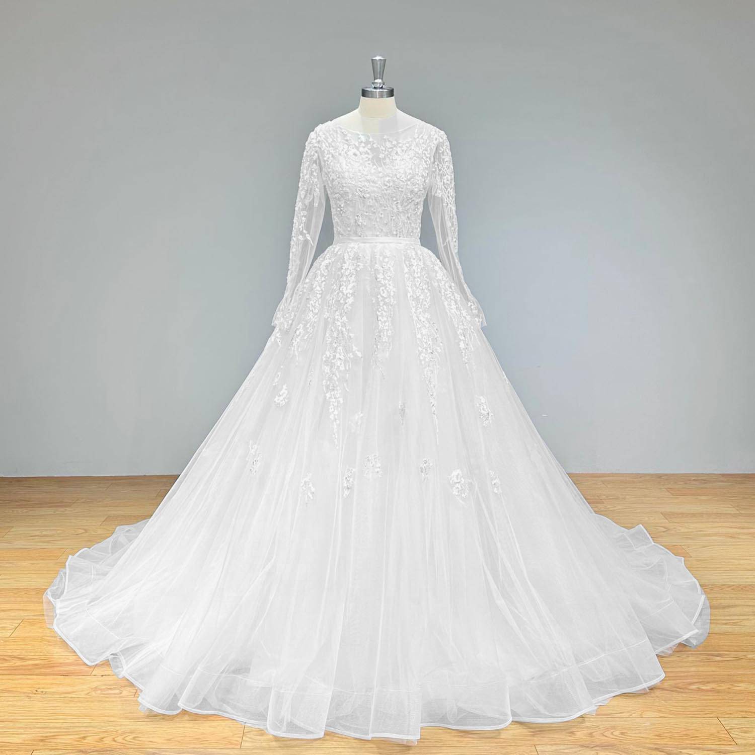 Front full-length view of a long-sleeve A-line tulle wedding dress with an intricate lace bodice and satin belt on a mannequin.