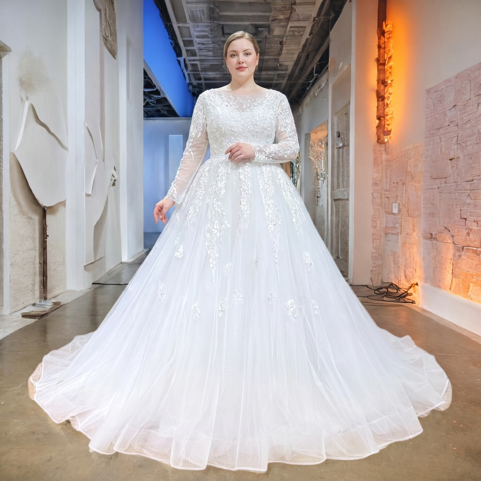 Full-length shot of a model wearing an elegant long-sleeve A-line tulle bridal gown with a defined waist and satin belt in a boutique setting.