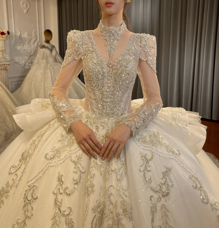 Close-up of a shimmering V-neck bridal gown bodice showcasing intricate silver beading, reflective sequins, and sheer beaded long sleeves.