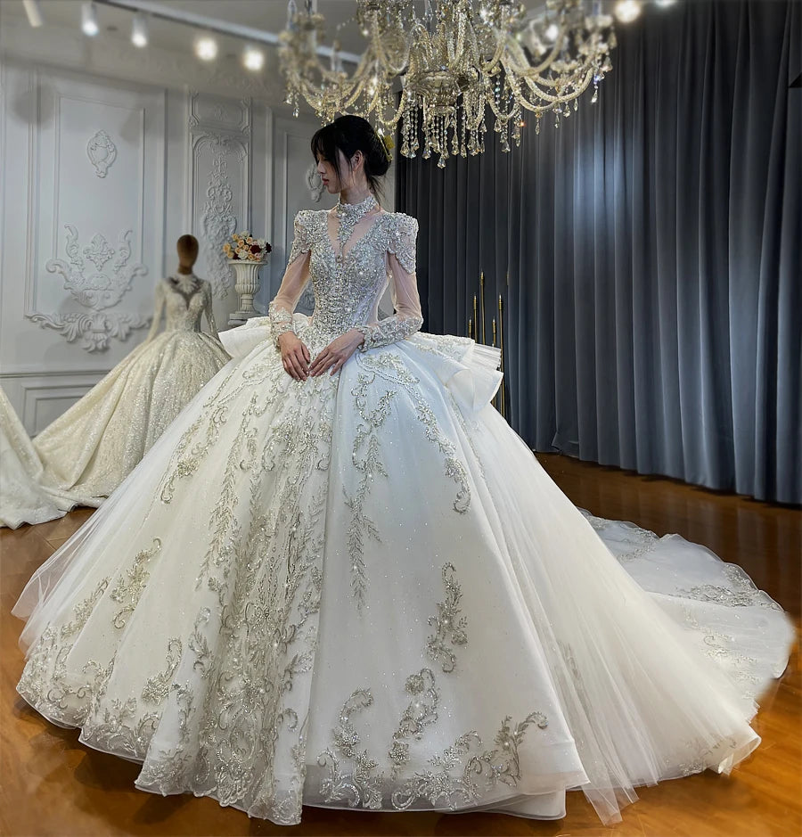Full frontal view of a luxury beaded ball gown wedding dress with a V-neckline and structured long sleeves on a professional bridal mannequin.