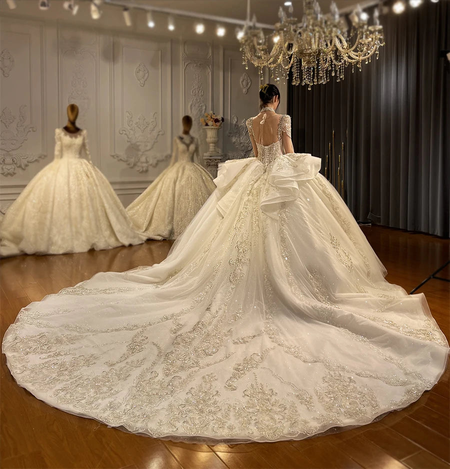 Majestic back view of a luxury wedding gown highlighting a grand ruffled cathedral train and an elegant lace-up corset back design.