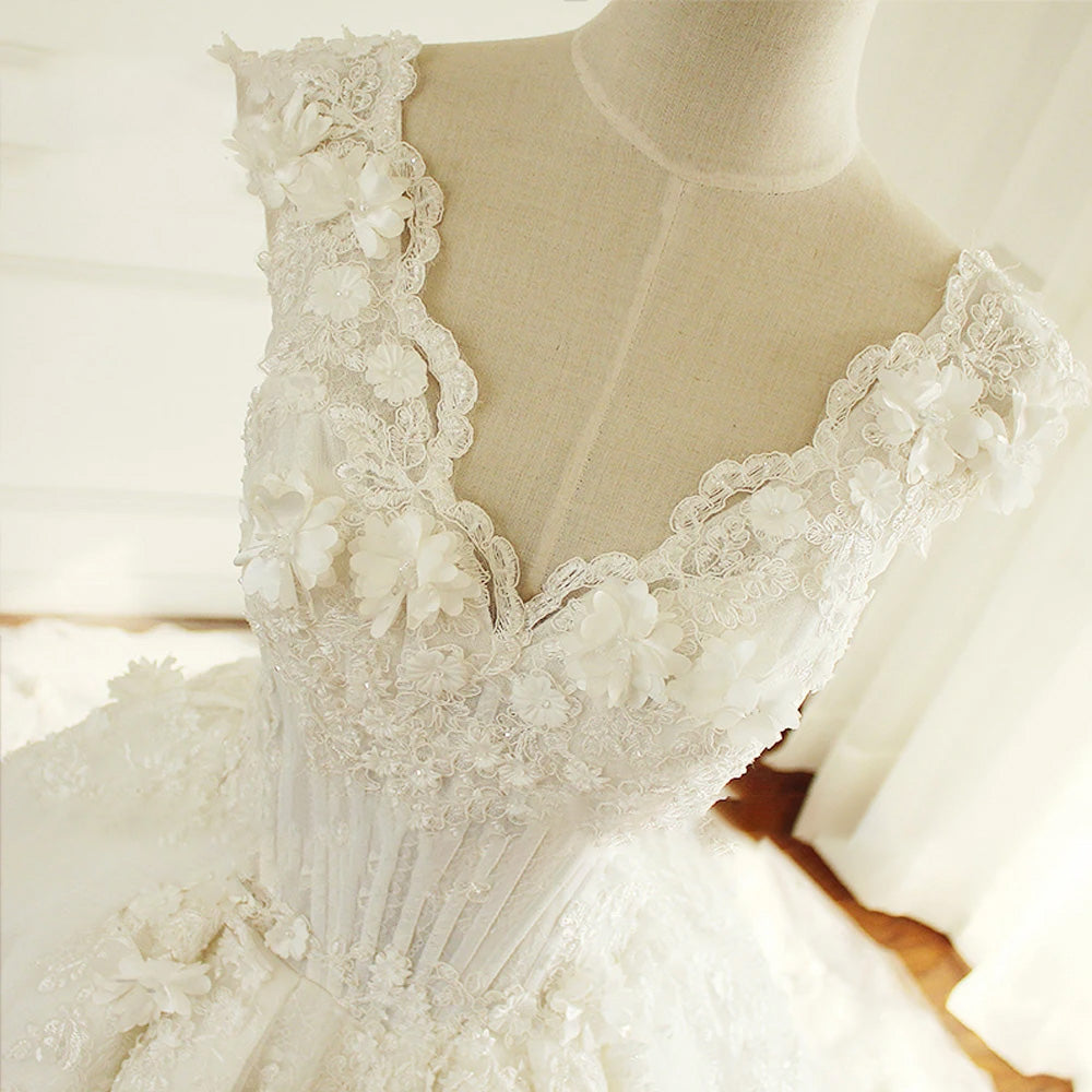A mannequin display showing an elegant V-neck princess wedding dress, highlighting the detailed lace flowers on the bodice and a full A-line skirt.