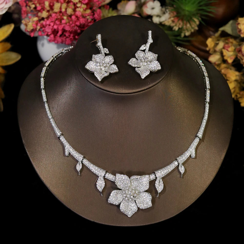 Luxury white floral CZ bridal necklace and earring set displayed on a dark jewelry stand
