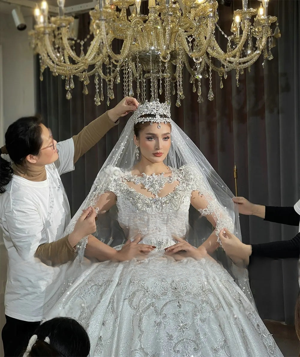 Close-up shot of the high-neck bodice of a crystal-encrusted wedding dress, showcasing detailed lace appliqué and high-end hand-beaded craftsmanship
